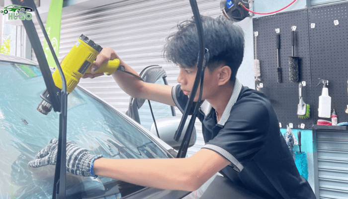 Kỹ thuật viên tại Gara Hugo Auto đang tiến hành kiểm tra và tẩy ố mốc kính lái trước khi lắp đặt gạt mưa mới cho khách hàng. Gạt mưa magic